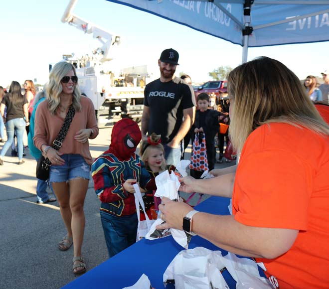 Lonnie Field, a CVEC engineering technician, and his wife, Sarah, watch as their children accept treat bags from Stacy Walter, manager of member services.